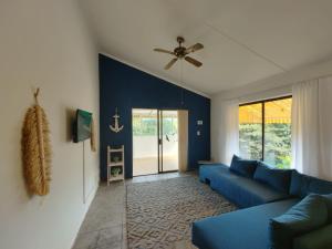 a living room with a blue couch and a ceiling fan at Cheerful 2 bedroom cottage with a communal pool in Hibberdene
