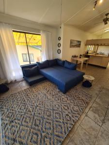 a living room with a blue couch and a rug at Cheerful 2 bedroom cottage with a communal pool in Hibberdene