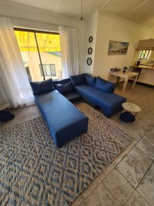 a living room with blue couches and a rug at Cheerful 2 bedroom cottage with a communal pool in Hibberdene