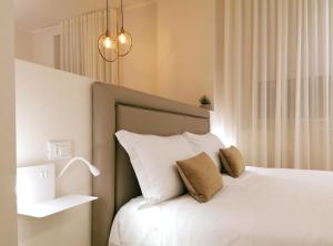 a bedroom with a bed with white sheets and pillows at Palazzo Cortesi Boutique Hotel in Macerata