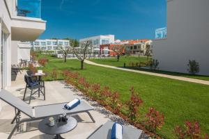 a patio with a table and chairs and a lawn at Maj Luxury Residence in Poreč