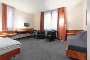 エッセンにあるHotel Böll Essenのベッドとデスクが備わるホテルルームです。