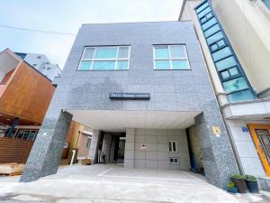 a gray building with a large entry way at Petit House in Sokcho