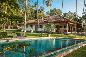 a villa with a swimming pool in front of a house at Rice House in Habaraduwa