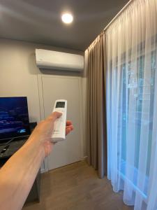 une personne tenant une télécommande devant une fenêtre dans l'établissement Apartment w-Terrace I Air Condition I New building I Self Check-In, à Birštonas