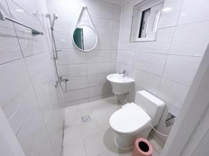 a white bathroom with a toilet and a sink at Petit House in Sokcho
