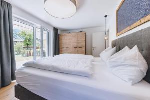 a bedroom with a large white bed with a large window at M1 - Mountain Living in Rauris