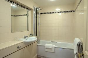 ein Badezimmer mit einem Waschbecken, einer Badewanne, einem WC und einem Spiegel in der Unterkunft Rose of York in Richmond upon Thames
