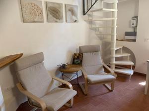 a living room with two chairs and a spiral staircase at In piazza Casale Marittimo in Casale Marittimo