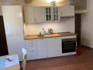 a kitchen with white cabinets and a sink and a stove at In piazza Casale Marittimo in Casale Marittimo