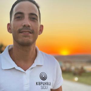 a man wearing a polo shirt with the sunset in the background at Kapuhala Sicily in Marzamemi