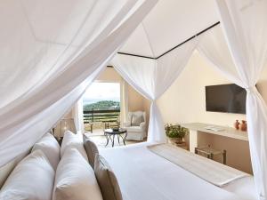 a bedroom with a bed with a view of the ocean at Grecotel Daphnila Bay in Dassia