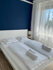 a white bed with two towels on it with a window at Élmény Balaton Hotel in Alsóörs