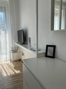 a white room with a bed and a television at Élmény Balaton Hotel in Alsóörs