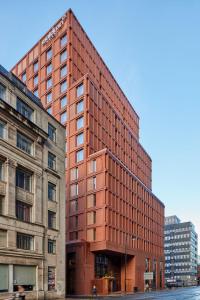 a tall red brick building next to two buildings at Maldron Hotel Manchester City Centre in Manchester