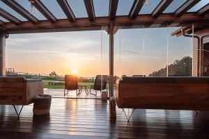 eine Terrasse mit Blick auf den Sonnenuntergang durch Fenster in der Unterkunft Hotel Rural La Sobreisla in Puerto de Vega
