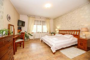 a bedroom with a bed and a desk and a television at Penzion Sonáta in Luhačovice