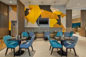 a restaurant with blue chairs and tables and a tv at Maldron Hotel Manchester City Centre in Manchester