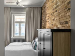 numa l Root Rooms & Apartments في براغ: غرفة نوم بسرير وجدار من الطوب