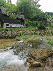 a river with a waterfall in front of a house at San Korana in Plitvička Jezera