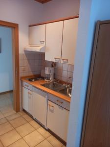 a small kitchen with white cabinets and a sink at Gästehaus Annette Hermes-Hoffmann in Trittenheim