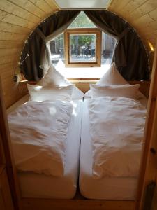2 camas blancas en una habitación pequeña con ventana en Übernachten im Weinfass en Volkach