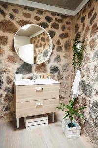 a bathroom with a sink and a mirror on a stone wall at Apartamentos El Callao II Suites in La Asomada