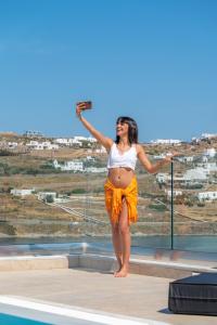 a pregnant woman standing on the edge of a swimming pool at CORFOS BLUE MYKONOS in Ornos