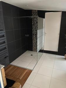 uma casa de banho com um chuveiro e uma porta de vidro em Le Cosily jacuzzi et sauna privatif em Cuvilly
