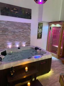 a large jacuzzi tub in a room with candles at Le Cosily jacuzzi et sauna privatif in Cuvilly