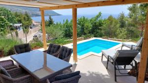 a patio with a table and chairs and a swimming pool at Lavanda Mobile Homes & Villas in Orebić