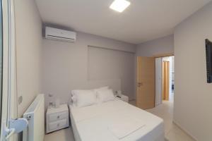 a white bedroom with a bed and a window at Althea Suites by RentalsPro- Nea Moudania Halkidiki in Nea Moudania