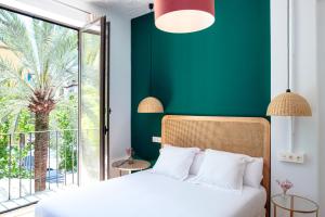 een slaapkamer met een wit bed en een groene muur bij Casa de la Romanilla in Granada
