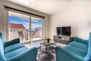 a living room with blue chairs and a large window at Apartman Vischetti in Cres