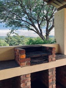 a brick fireplace with a tree in the background at Bergdale Cottages in Hazyview