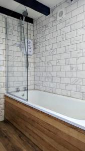 La salle de bains blanche est pourvue d'une baignoire et d'un mur en briques blanches. dans l'établissement Yetland Farm Holiday Cottages, à Combe Martin