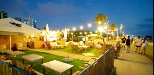 a group of people walking on a sidewalk near a beach at night at beach front tel aviv bat yam apartment -hotel 39 in Bat Yam +138 photos