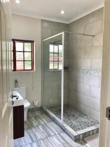 a bathroom with a shower with a toilet and a sink at Bergdale Cottages in Hazyview