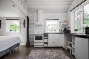 Cozy holiday house close to nature in Ödeshög, Gränna في Ödeshög: مطبخ مع دواليب بيضاء وسرير في الغرفة