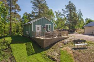a green tiny house with a deck in the yard at Cozy holiday house close to nature in Ödeshög, Gränna in Ödeshög