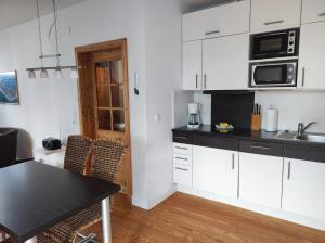 a kitchen with white cabinets and a black table at Haus Sommerwind in Norderney