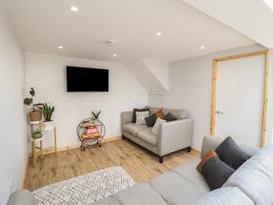 a living room with a couch and a tv on a wall at Little Nook in Corwen