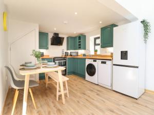 a kitchen with green cabinets and a table at Little Nook in Corwen