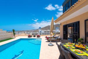 a swimming pool with a table and chairs next to a house at TORVISCAS SUNSET VILLA & Jacuzzi in Adeje