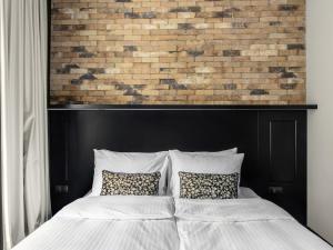 a bed with two pillows in front of a brick wall at Numa Prague Root in Prague