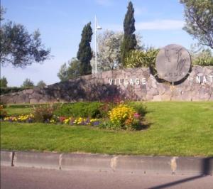 un cartel de bienvenida en un parque con flores en La Cage Village Naturiste, en Cap d'Agde