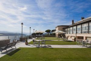Un patio con mesas y sillas y un edificio. en Parador de Ribadeo, en Ribadeo