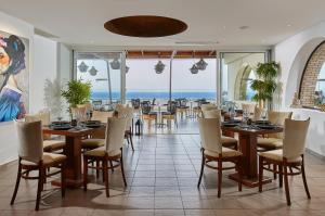 Un restaurante con mesas y sillas y vista al mar. en Blue Marine Resort and Spa Hotel, en Agios Nikolaos