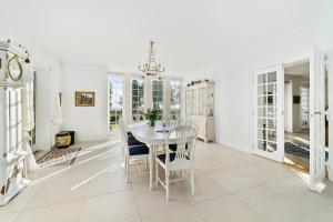 a white dining room with a table and chairs at DENMARK SEA FRONT ENCHANTING - Beach Villa in Solrød Strand