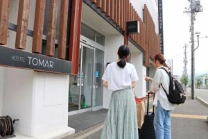 Twee vrouwen staan buiten een winkel. bij Hostel Tomar in Furano